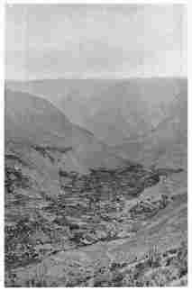 Fig. 29—Cotahuasi on the floor of the Cotahuasi canyon. The even skyline of the background is on a rather even-topped lava plateau. The terrace on the left of the town is formed on limestone, which is overlain by lava flows. A thick deposit of terraced alluvium may be seen on the valley floor, and it is on one of the lower terraces that the city of Cotahuasi stands. The higher terraces are in many cases too dry for cultivation. The canyon is nearly 7,000 feet (2,130 m.) deep and has been cut through one hundred principal lava flows.