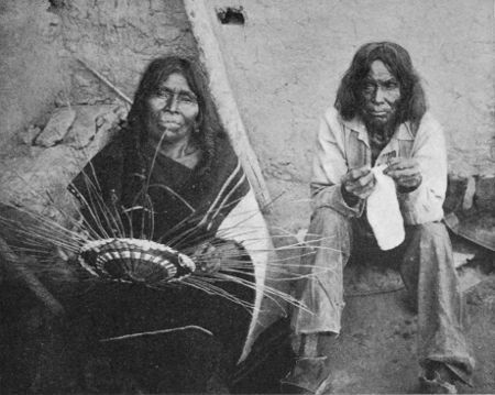 Hopi Woman weaving Basket, her Husband knitting Stockings.
