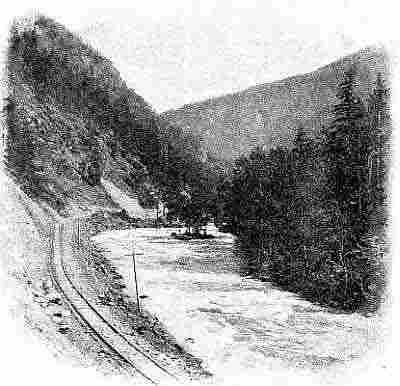 Mountain river, railroad and telephone poles running on left side, small islet at river bend.